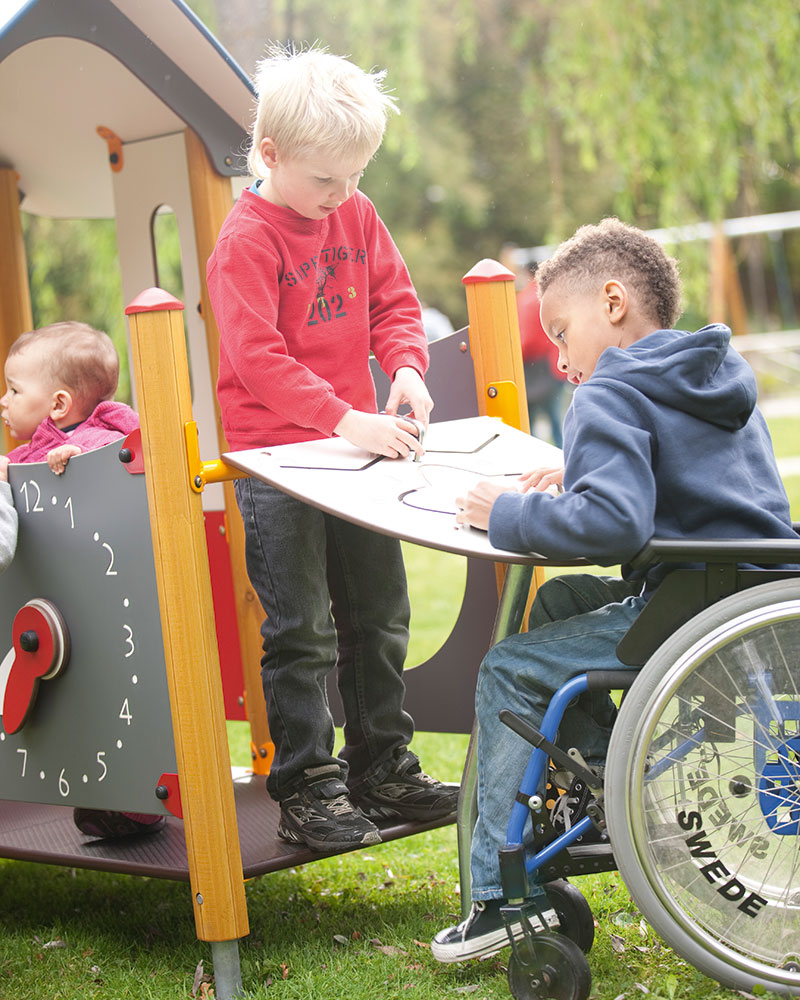 Kinderen spelen op speelpanelen, een van hen zit in een rolstoel.